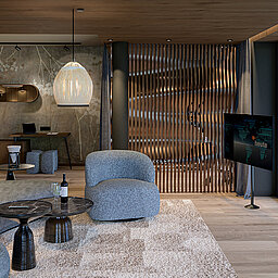 Wohnbereich der neuen Sky Suite Wohnbereich einer Sky Suite mit gemütlichem Sofa, Holzelementen und Panoramafenstern mit Bergblick.