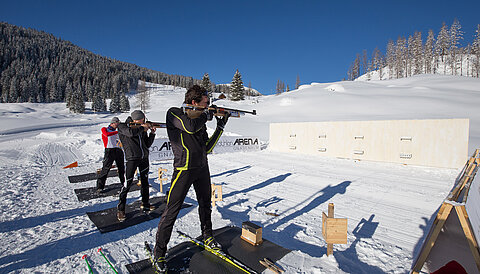 Biathleten zielen mit Gewehren auf Schießstand im Schnee