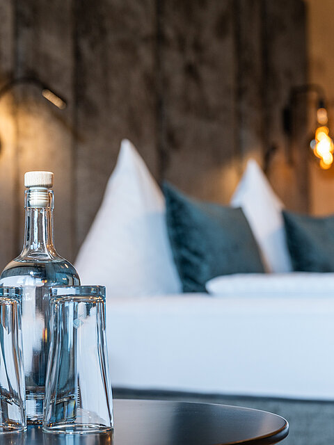 Ein Beistelltisch mit Gläser und einer Wasserflasche in der Mountain Loft Familiysuite im Lürzerhof