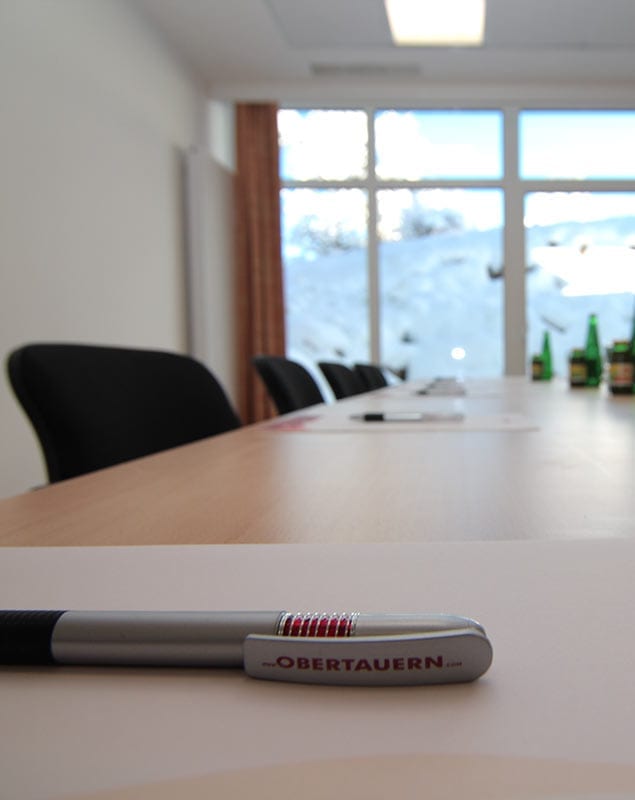 Modern seminar room with conference table, writing materials, and a view of the snow-covered landscape at Hotel Lürzerhof